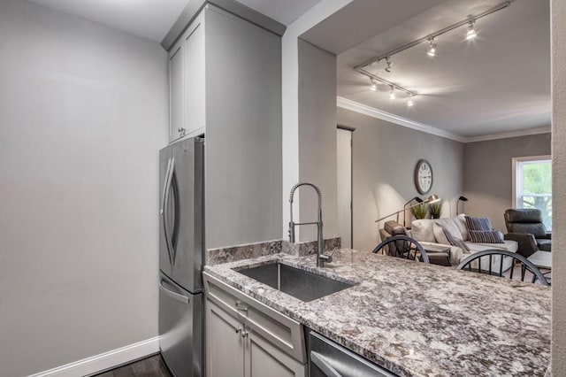 kitchen featuring freestanding refrigerator, ornamental molding, light stone counters, a sink, and open floor plan