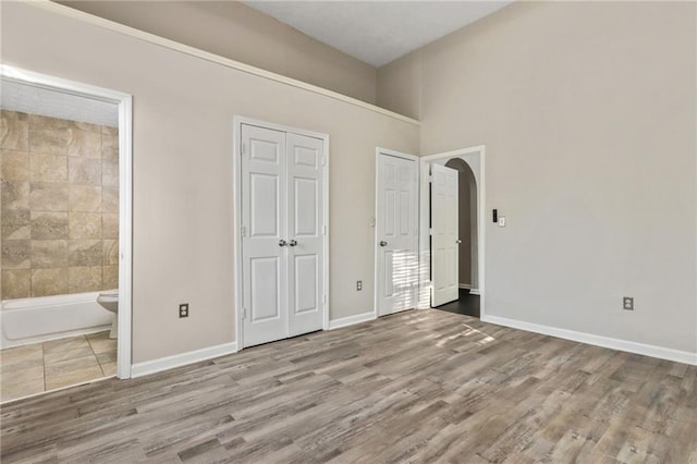 unfurnished bedroom with connected bathroom and light wood-type flooring