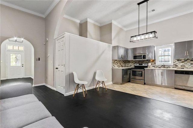 kitchen featuring hanging light fixtures, backsplash, plenty of natural light, and appliances with stainless steel finishes