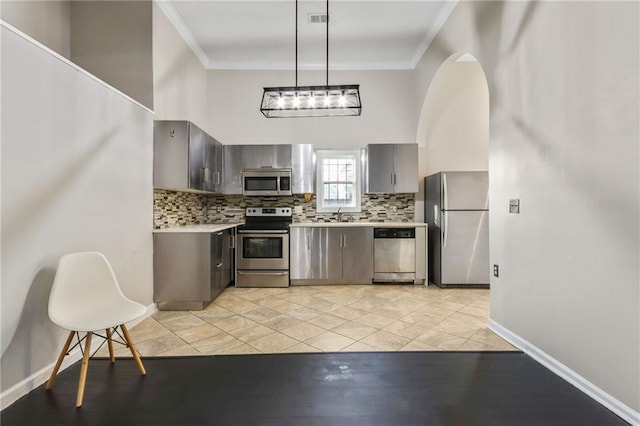 kitchen featuring tasteful backsplash, decorative light fixtures, crown molding, and appliances with stainless steel finishes