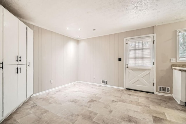 foyer entrance featuring a textured ceiling and wood walls