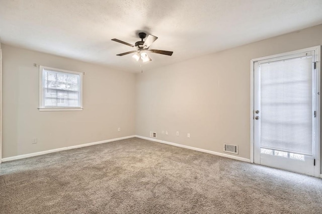 carpeted spare room featuring plenty of natural light and ceiling fan