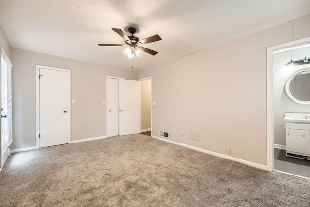 unfurnished bedroom with ceiling fan, ensuite bathroom, sink, and carpet floors