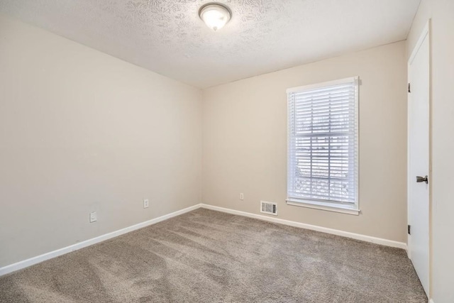 carpeted empty room featuring a textured ceiling