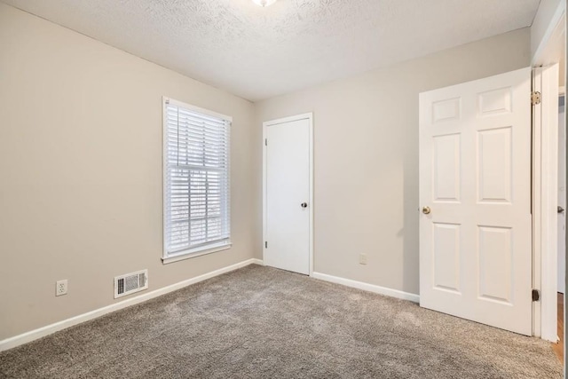 carpeted spare room with a textured ceiling