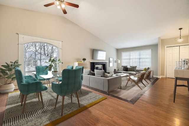 living room featuring dark wood-type flooring, ceiling fan, and vaulted ceiling