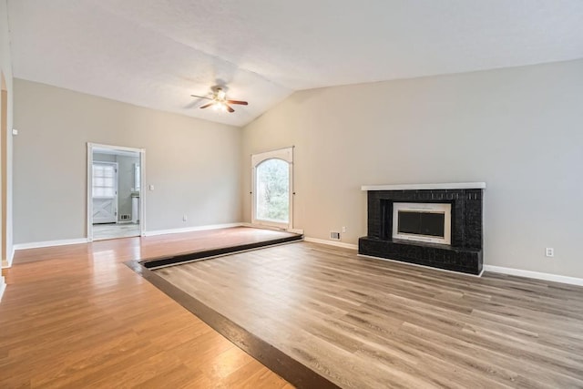 unfurnished living room featuring vaulted ceiling, ceiling fan, a fireplace, and hardwood / wood-style floors