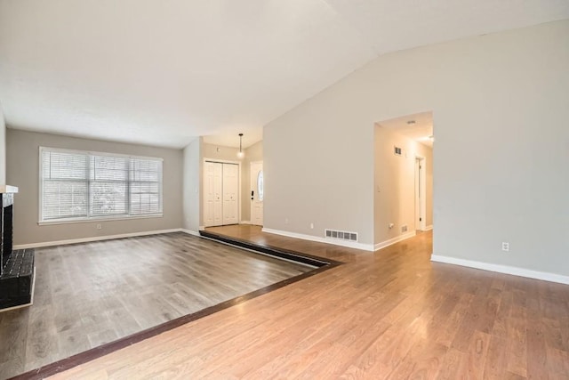 unfurnished living room featuring lofted ceiling, hardwood / wood-style floors, and a fireplace