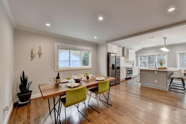 dining space with a wealth of natural light, visible vents, wood finished floors, and crown molding