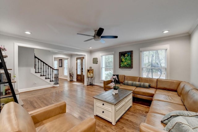 living room featuring light wood-type flooring, recessed lighting, crown molding, baseboards, and stairs