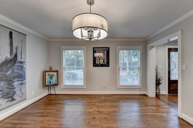 unfurnished room featuring a chandelier, crown molding, baseboards, and wood finished floors