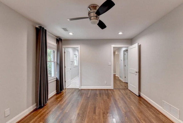 unfurnished bedroom with connected bathroom, wood finished floors, visible vents, and baseboards