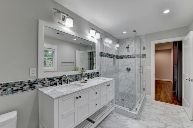 full bathroom with toilet, marble finish floor, backsplash, and a sink