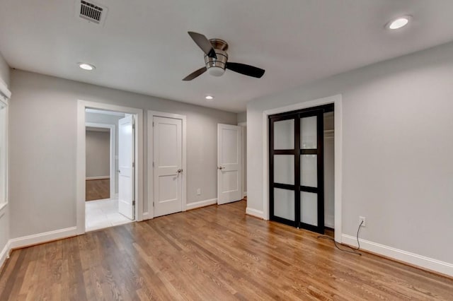 unfurnished bedroom with wood finished floors, visible vents, and baseboards