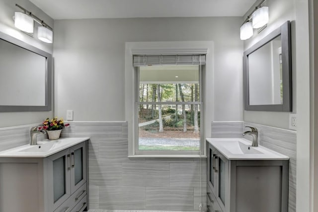 bathroom with a wainscoted wall, two vanities, and a sink