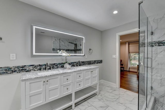 bathroom featuring a marble finish shower, marble finish floor, and a sink