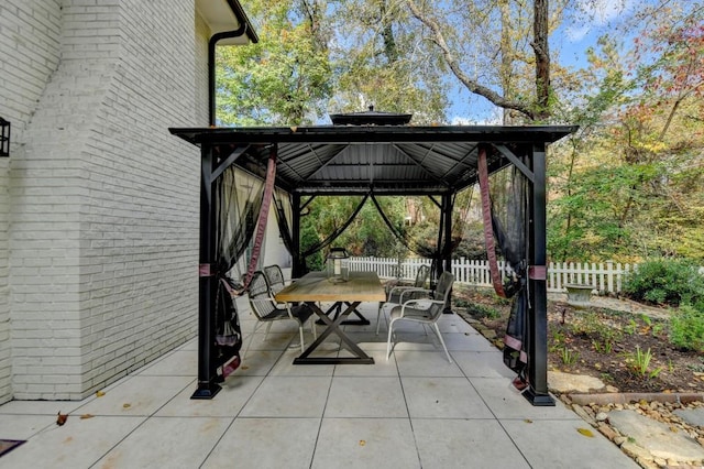 view of patio with a gazebo, outdoor dining area, and fence