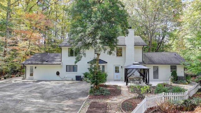 back of property featuring a gazebo, a patio, brick siding, and a chimney