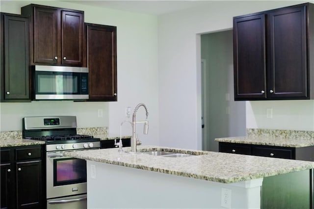 4417 Belcamp Rd, Fairburn, GA 30213 - kitchen with appliances with stainless steel finishes, an island with sink, light stone countertops, and dark brown cabinetry