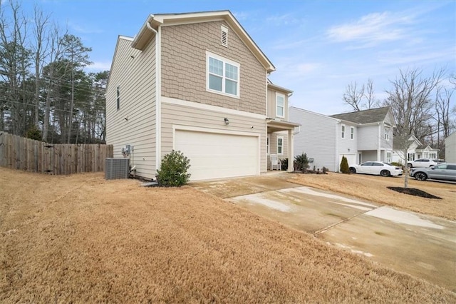 traditional-style home with concrete driveway, central air condition unit, an attached garage, and fence