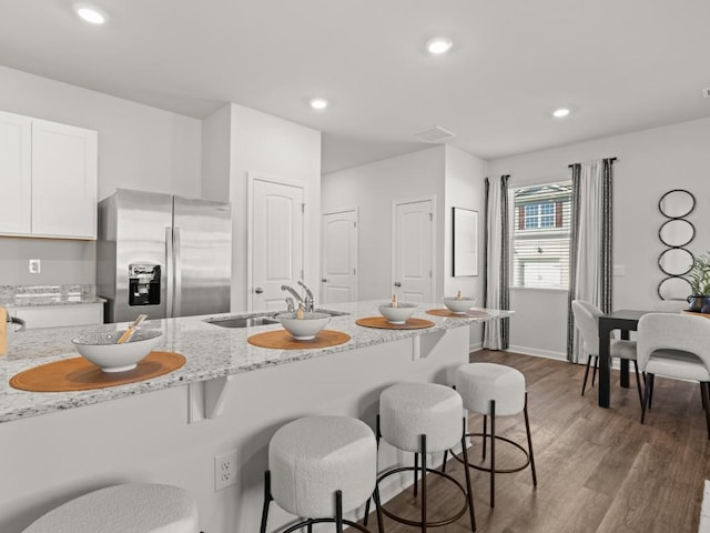 kitchen featuring sink, white cabinets, light stone counters, dark hardwood / wood-style floors, and stainless steel refrigerator with ice dispenser