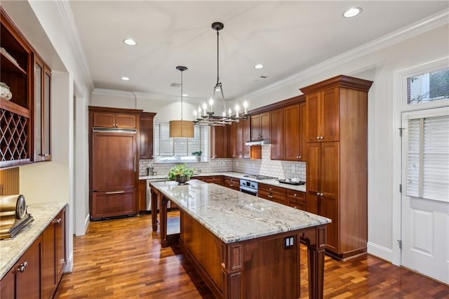 kitchen with dark wood-style floors, appliances with stainless steel finishes, ornamental molding, and a center island