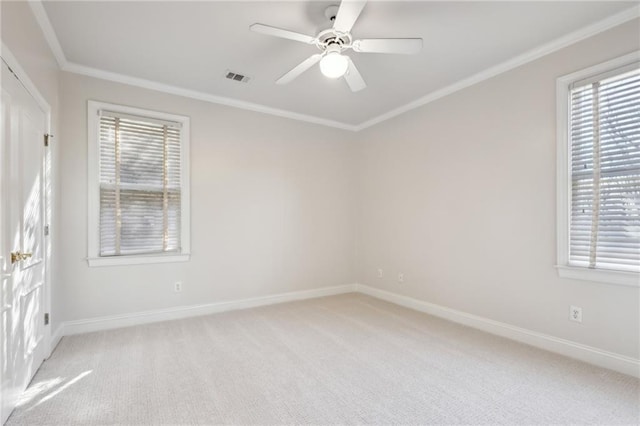 empty room with baseboards, visible vents, ceiling fan, ornamental molding, and light carpet