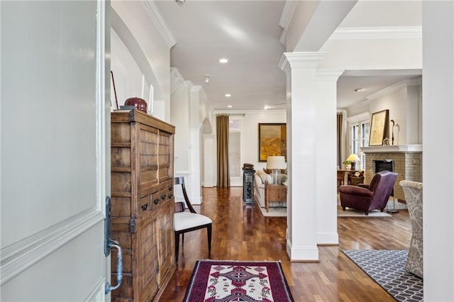 entrance foyer featuring wood finished floors, recessed lighting, crown molding, a fireplace, and ornate columns