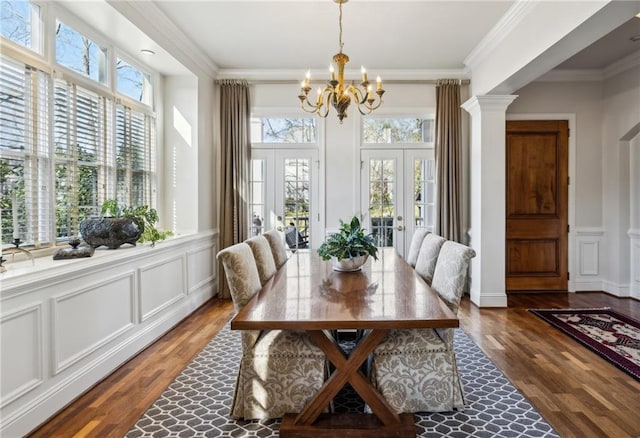 dining area featuring a decorative wall, french doors, crown molding, and an inviting chandelier