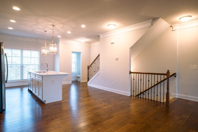 kitchen featuring crown molding, dark wood-type flooring, baseboards, light countertops, and a sink