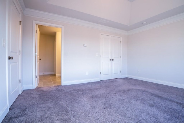 unfurnished bedroom featuring crown molding, carpet, baseboards, and a closet