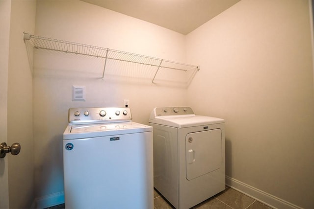 washroom featuring baseboards, separate washer and dryer, dark tile patterned floors, and laundry area