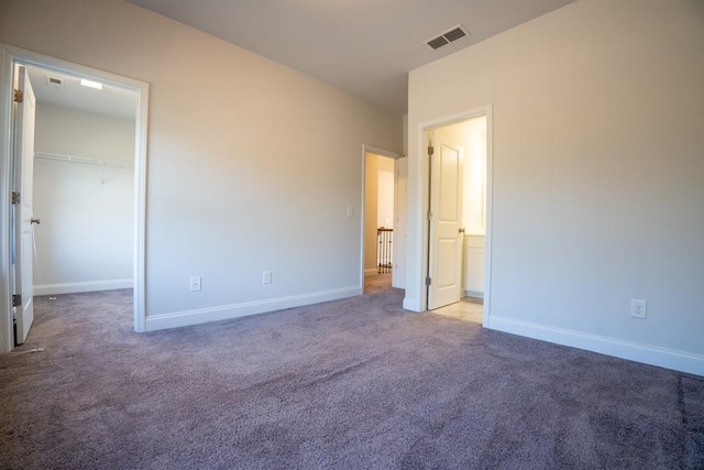 unfurnished bedroom featuring visible vents, baseboards, a walk in closet, and carpet