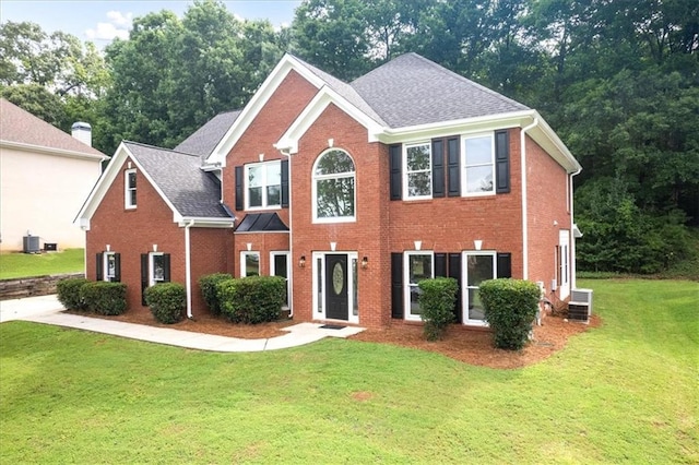 colonial home featuring brick siding, cooling unit, and a front yard