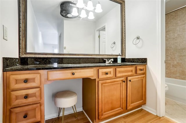 full bathroom with toilet, vanity, tiled shower / bath, and hardwood / wood-style floors