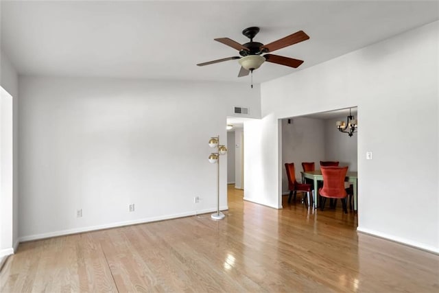 unfurnished living room with ceiling fan with notable chandelier and light hardwood / wood-style flooring