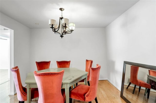 dining area with light wood-type flooring and a notable chandelier