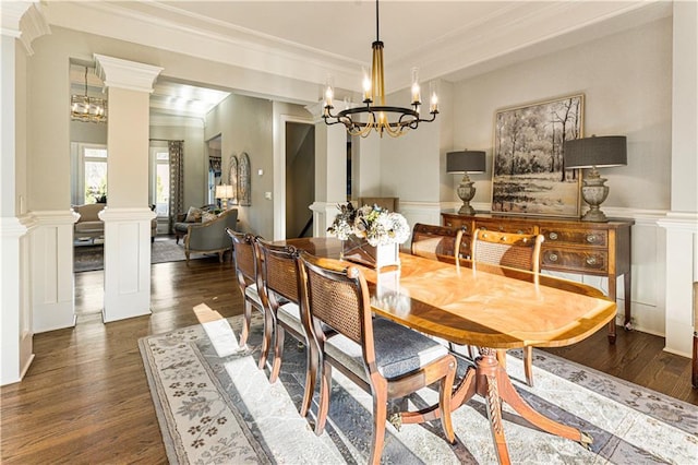 dining room featuring a chandelier, dark hardwood / wood-style flooring, crown molding, and decorative columns