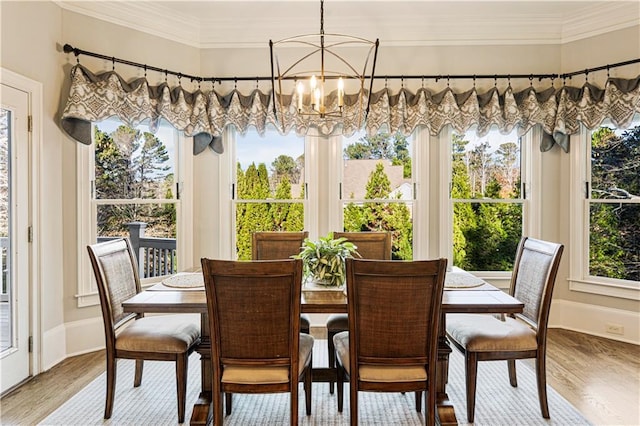 dining area with hardwood / wood-style floors, crown molding, and a notable chandelier