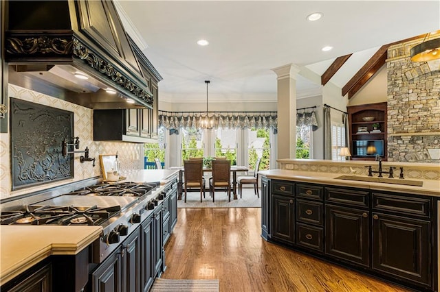 kitchen with sink, vaulted ceiling with beams, pendant lighting, extractor fan, and decorative backsplash