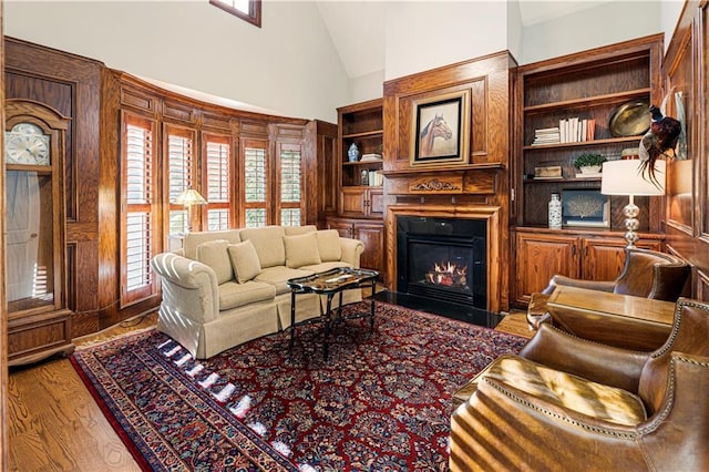 living room with built in features, hardwood / wood-style floors, and high vaulted ceiling