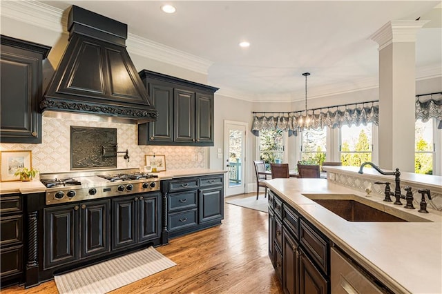 kitchen featuring sink, tasteful backsplash, light hardwood / wood-style floors, custom range hood, and stainless steel gas cooktop