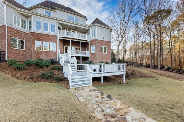 back of house featuring a yard, a balcony, and a wooden deck