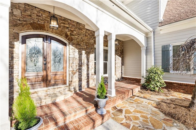 view of exterior entry with french doors and a porch