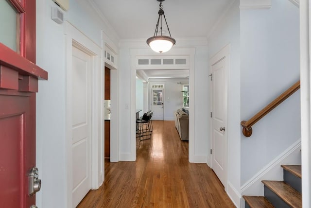 hallway featuring stairway, wood finished floors, baseboards, and ornamental molding