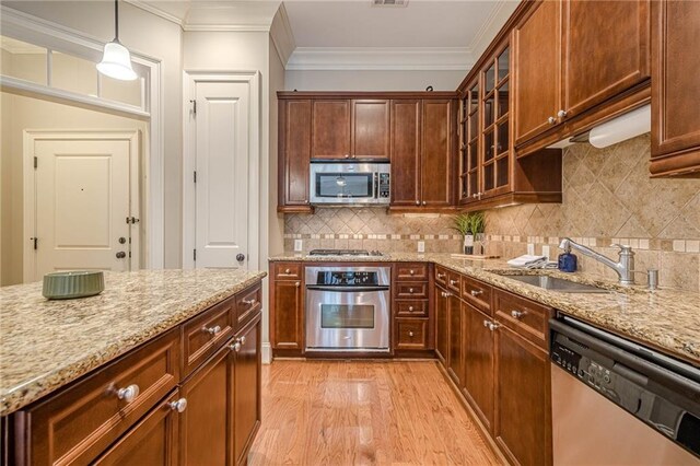 kitchen featuring crown molding, hanging light fixtures, light hardwood / wood-style flooring, appliances with stainless steel finishes, and a kitchen island