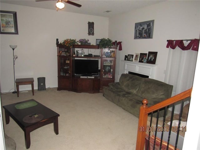 carpeted living room featuring ceiling fan and a fireplace