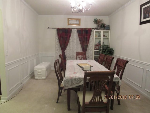 carpeted dining space with crown molding, a decorative wall, and an inviting chandelier