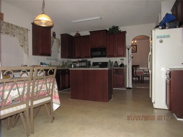 kitchen featuring black microwave, arched walkways, a sink, freestanding refrigerator, and a center island