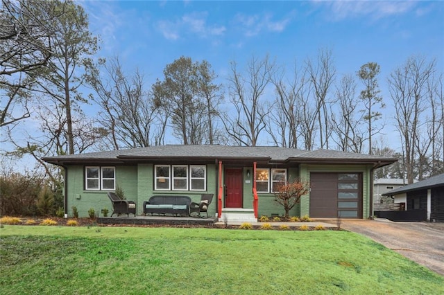 view of front of house featuring an attached garage, driveway, brick siding, and a front yard